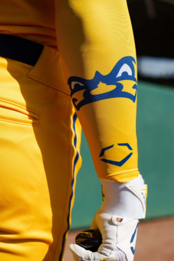 Yellow compression arm sleeve with blue graphic logo, worn on forearm
