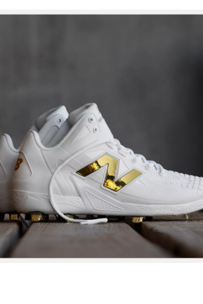 White baseball cleat side view with gold logo and lace-up closure