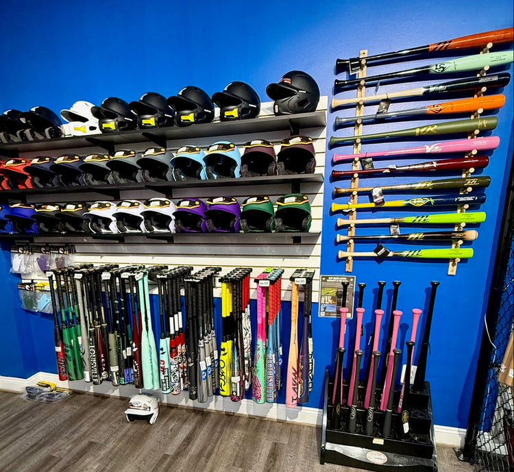 Display of baseball bats and helmets against a blue wall.