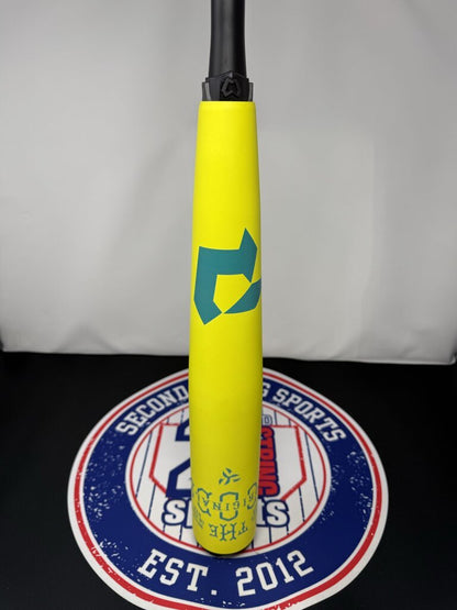 Yellow baseball bat with teal logo on barrel and black grip, upright against logo base