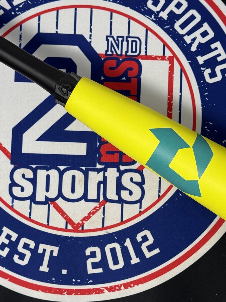 Close-up of yellow baseball bat barrel showing teal chevron logo and printed details