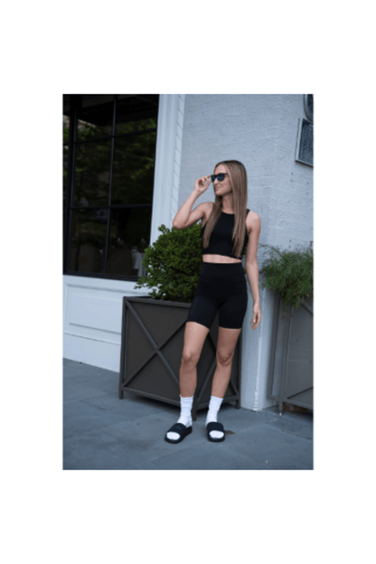 Black slides on a person’s feet, open-toe slide sandal