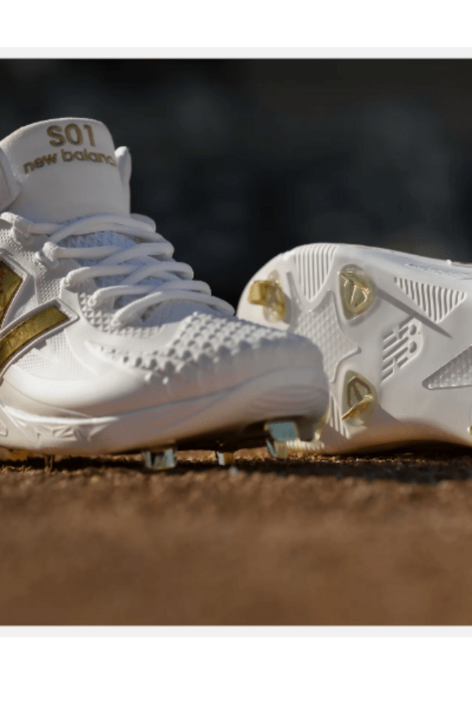 White baseball cleat toe and side with gold accents and metal studs
